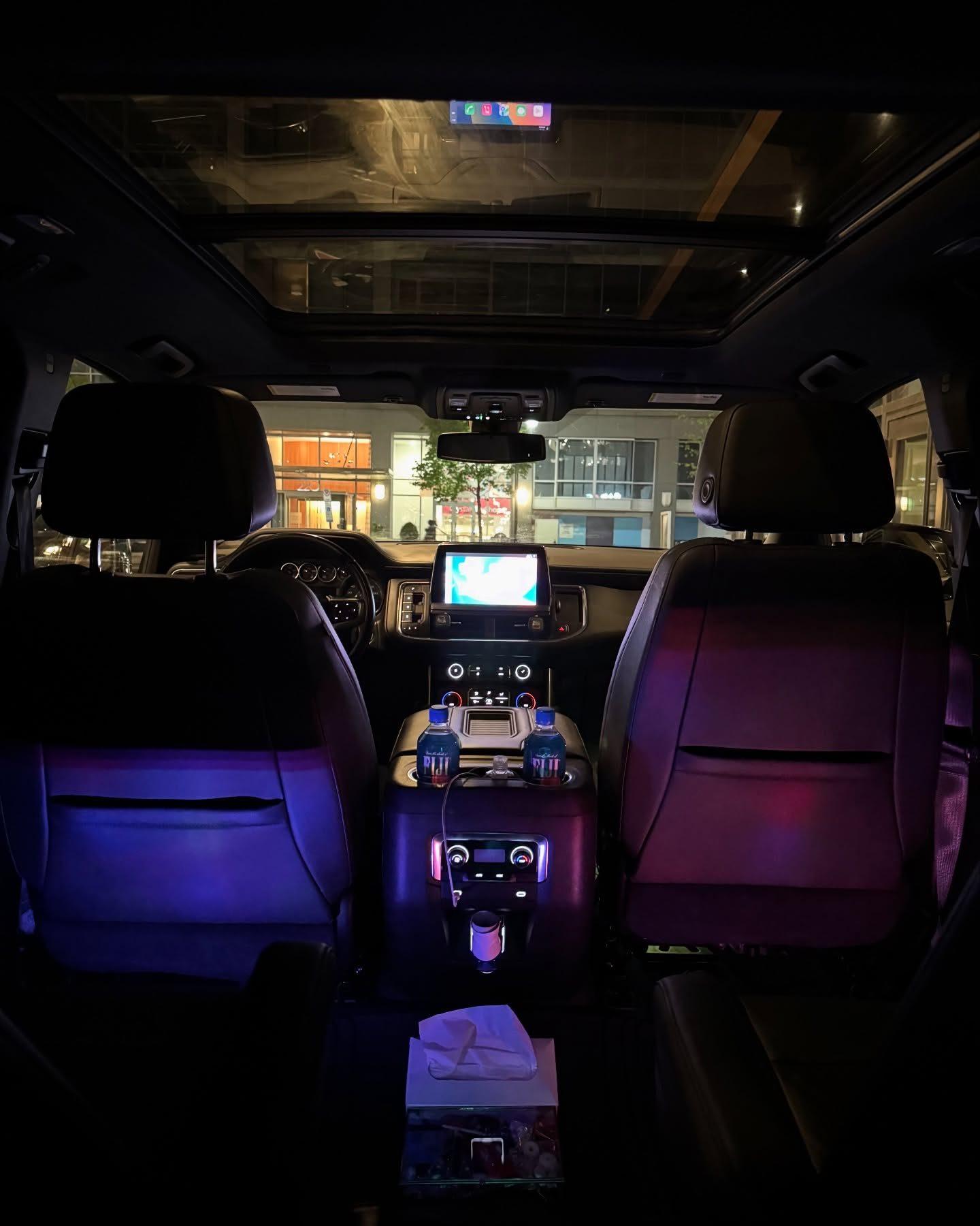 Executive SUV rear cabin at night with ambient lighting and chilled bottled water