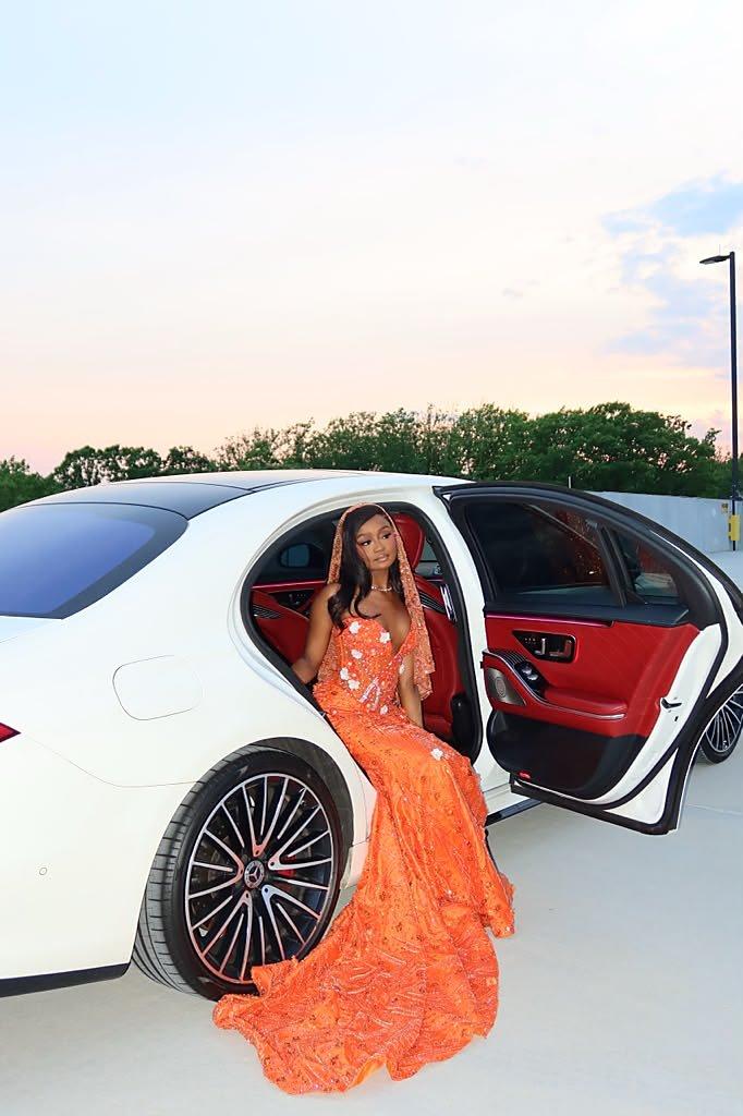 Open door of a white luxury sedan showing the red leather interior at dusk