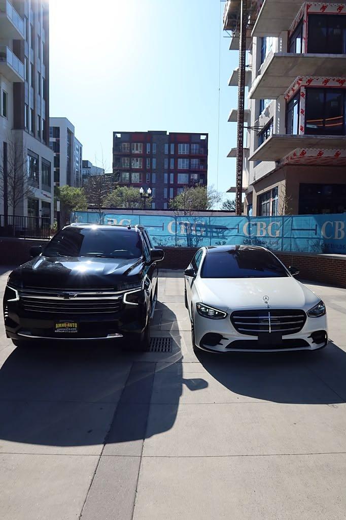 Black Chevrolet Suburban and white Mercedes-Benz S-Class ready in daylight