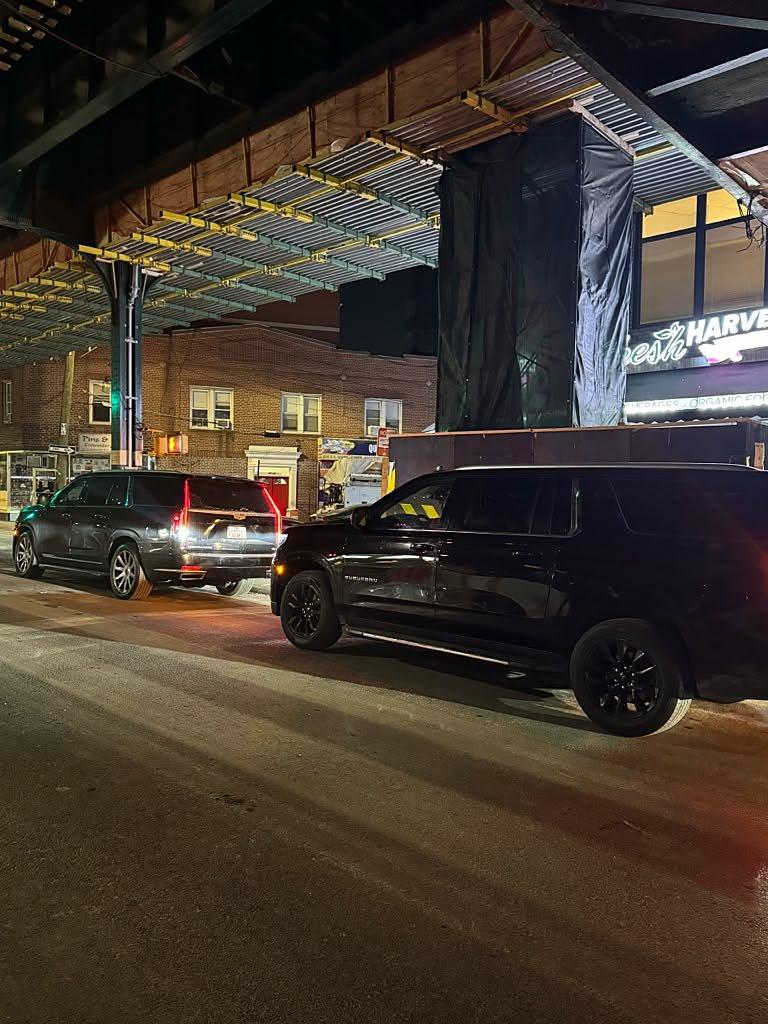 Black Cadillac Escalade and Chevrolet Suburban on a city street at night